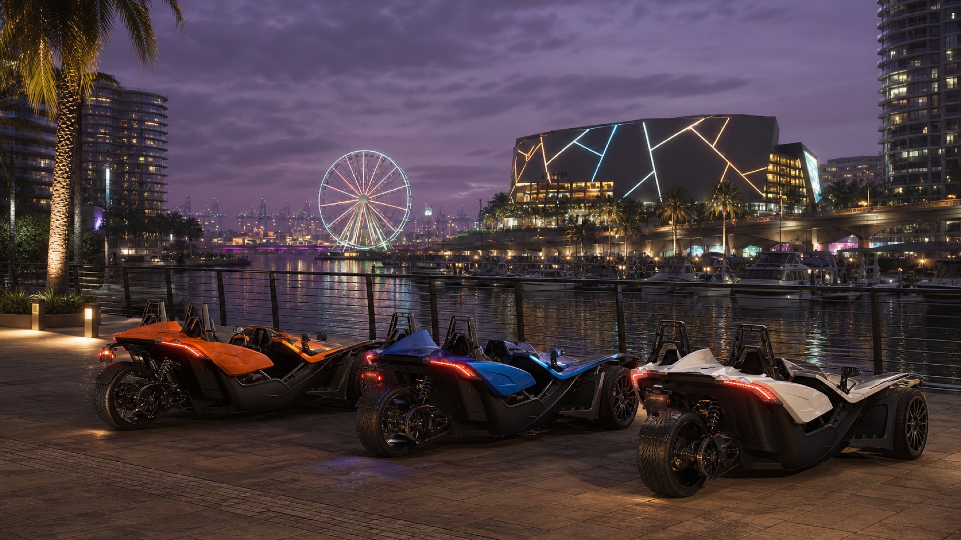 Three Polaris Slingshots parked on the Bayside waterfront promenade at dusk, the observation wheel and arena lit behind