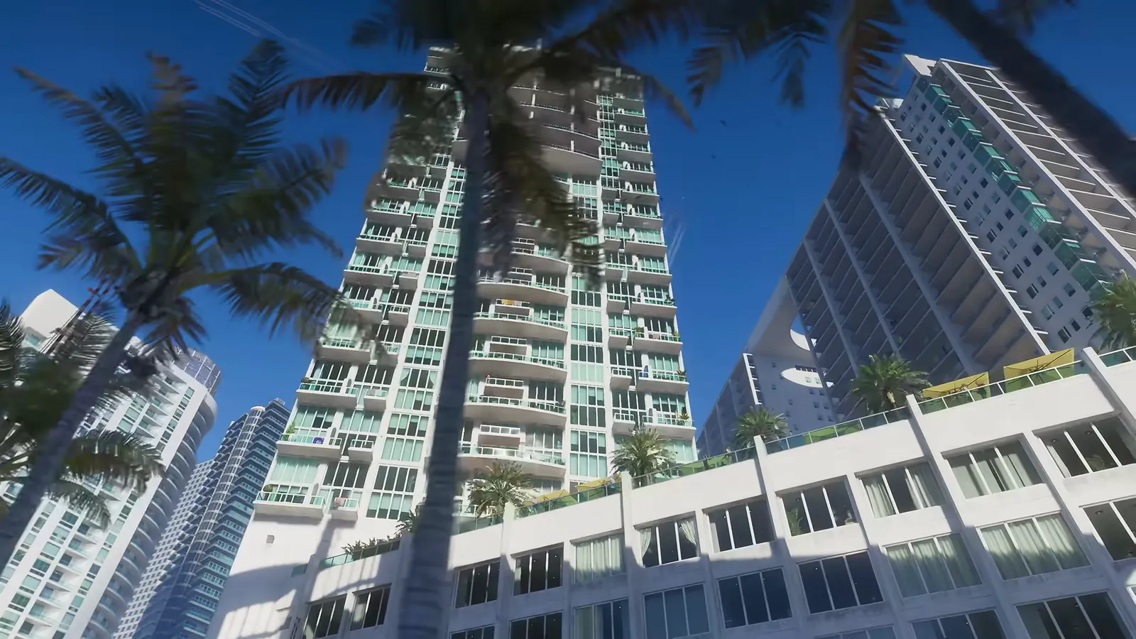 Brickell on the River in GTA VI: Low-angle view up at teal-glass Tequesta apartment towers framed by palms.