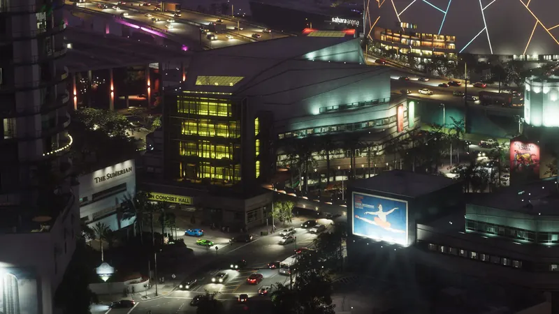 The Sumerian in GTA VI: The Sumerian's lit sign at the foot of a bayfront tower next to the arts center's concert hall.