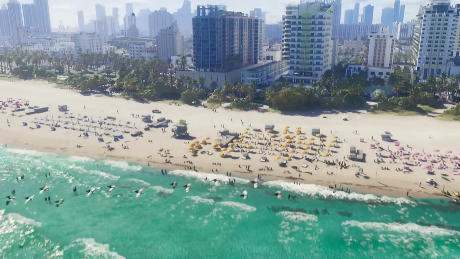 Ocean Beach in GTA VI: Aerial over Ocean Beach: lifeguard stands and rows of umbrellas on the sand, with the Vice Beach hotel towers behind.