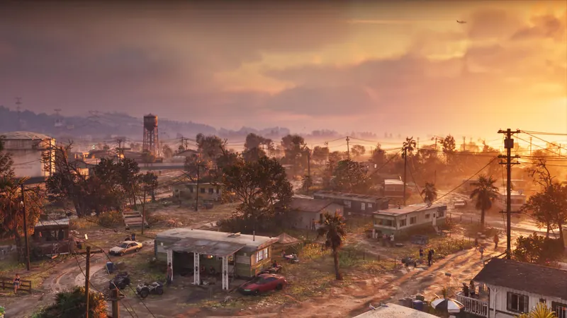 Sunset aerial over a sprawling low-rise town with a gas station and power lines.